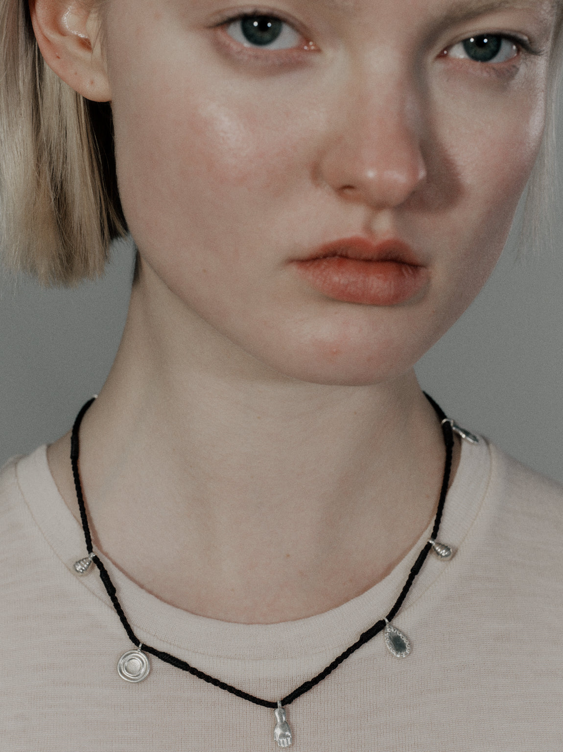 Silver charms on black cord choker necklace with teardrop pendants