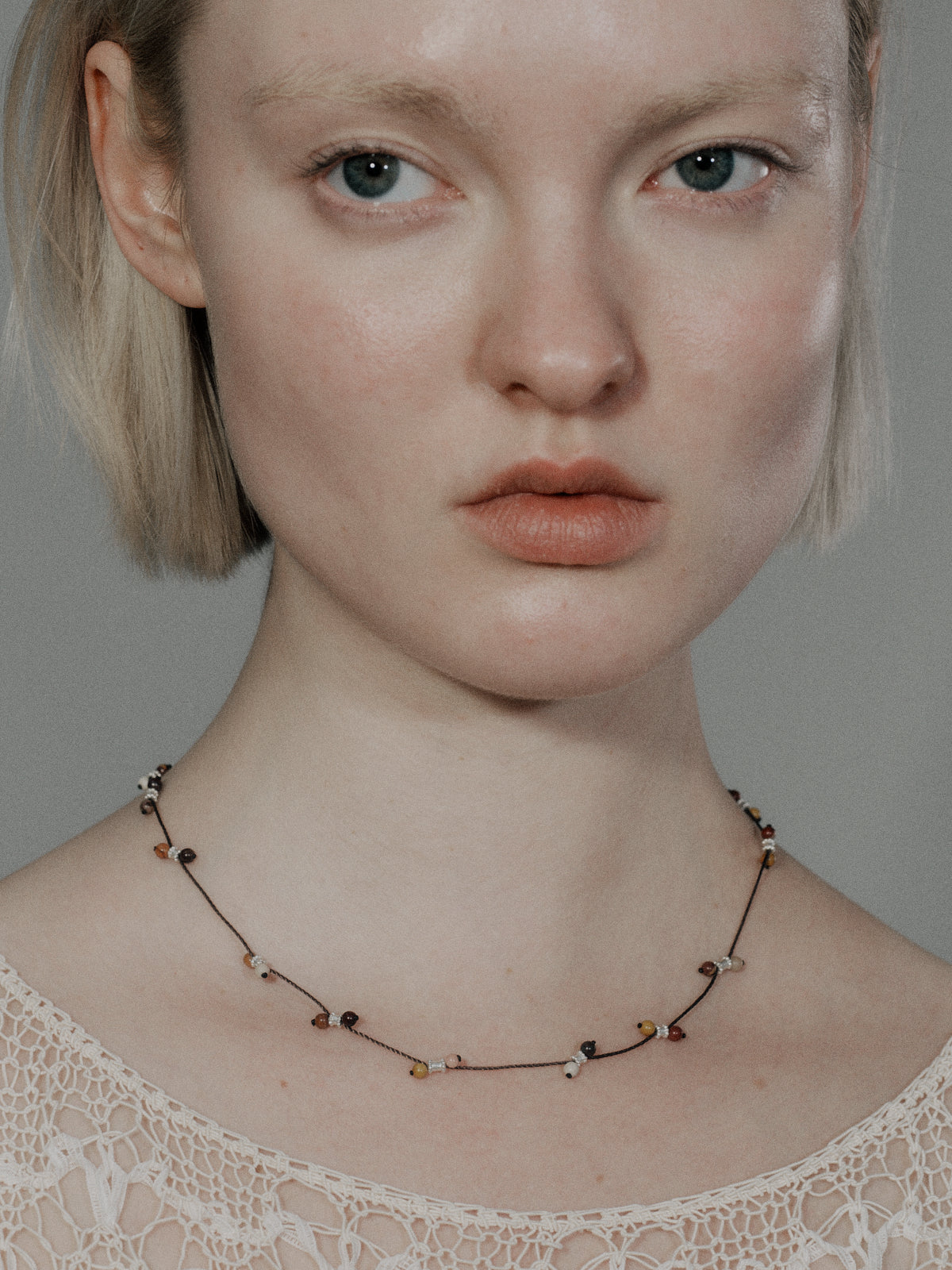 Silver-tone braided necklace with black and yellow beads on a slim cord chain