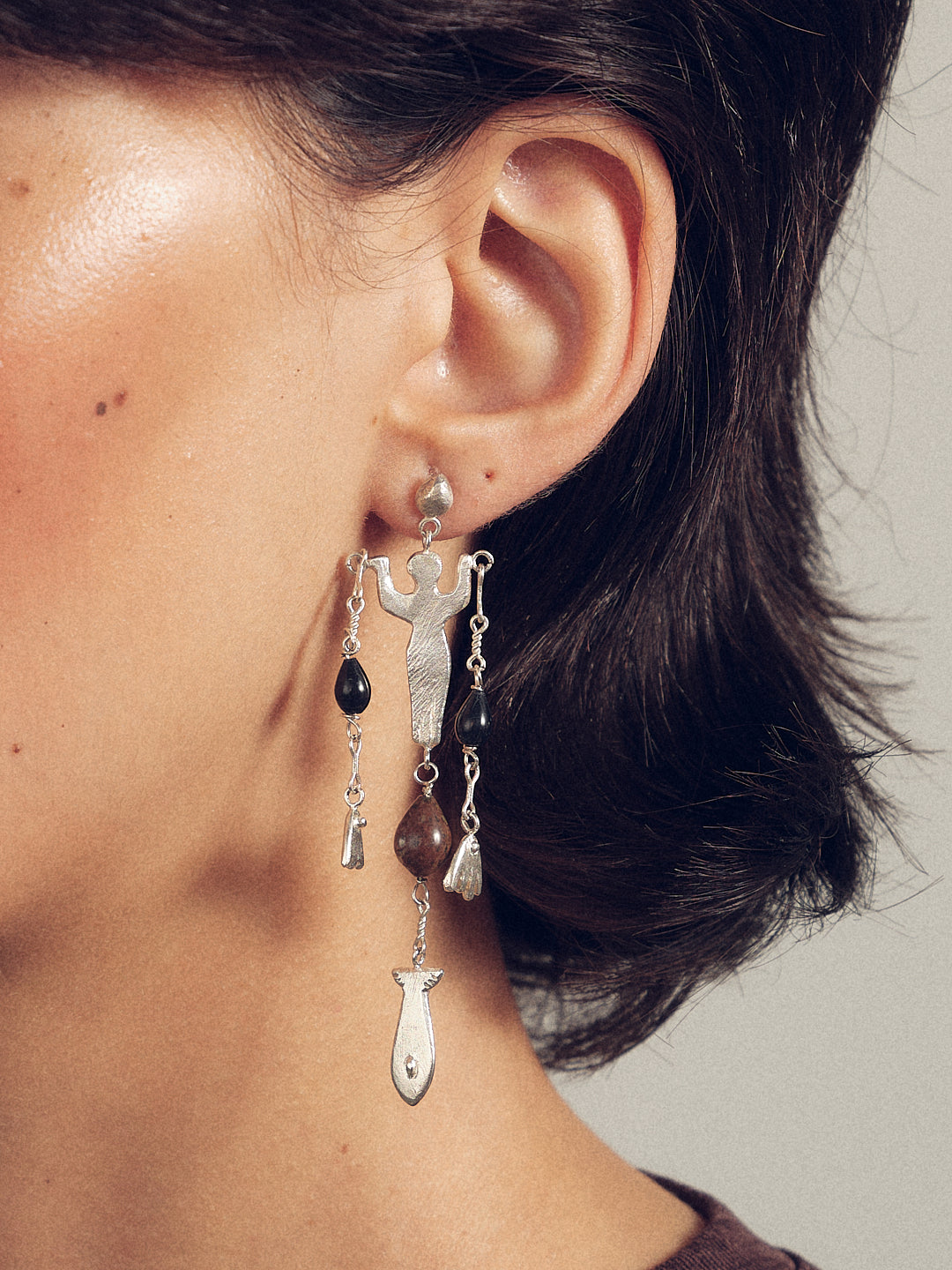 Silver-tone circus earrings close-up with cross charm, black beads, and long dangles