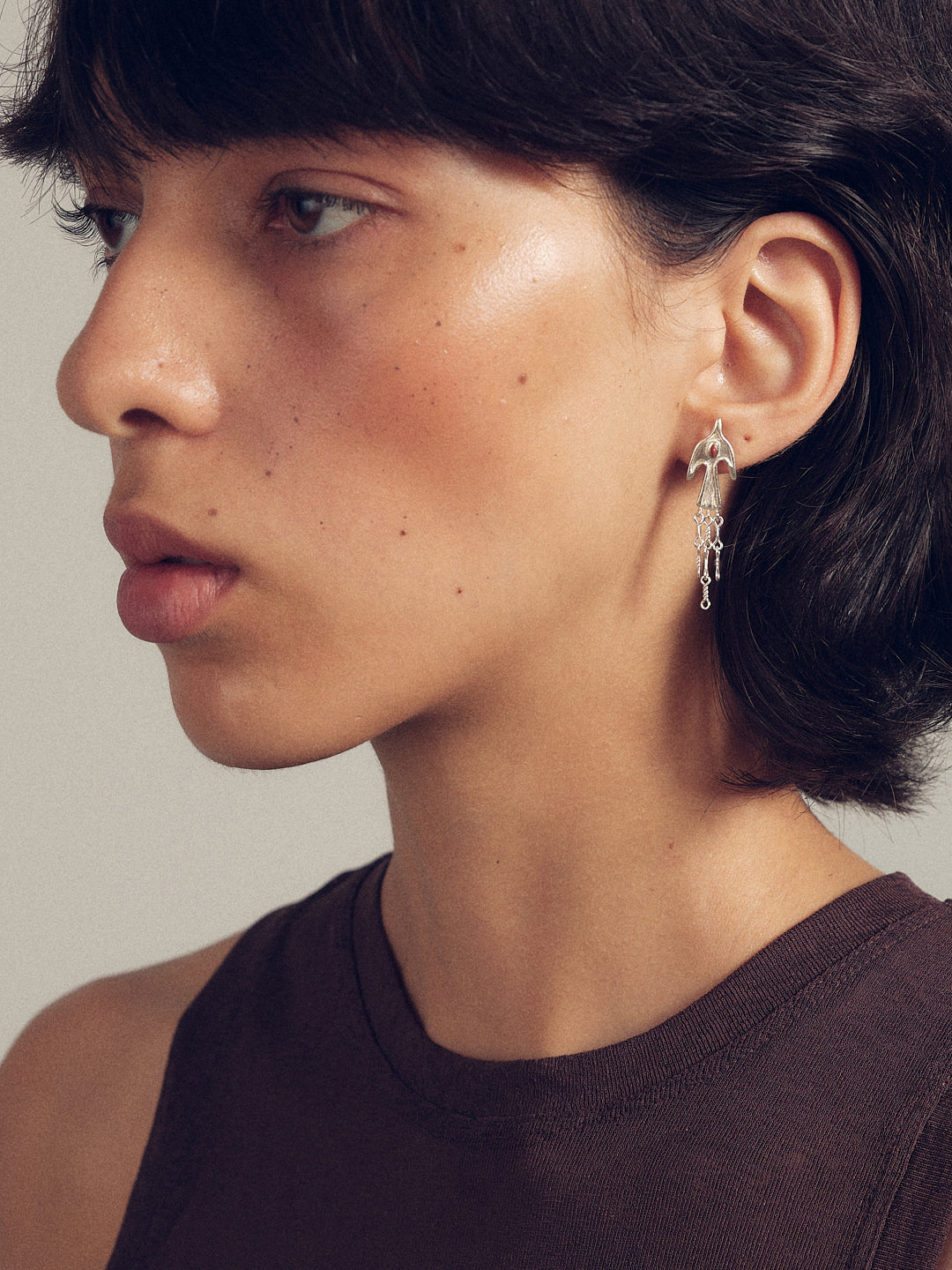 Silver bird tassel earrings with hanging charms and small loop at the ear