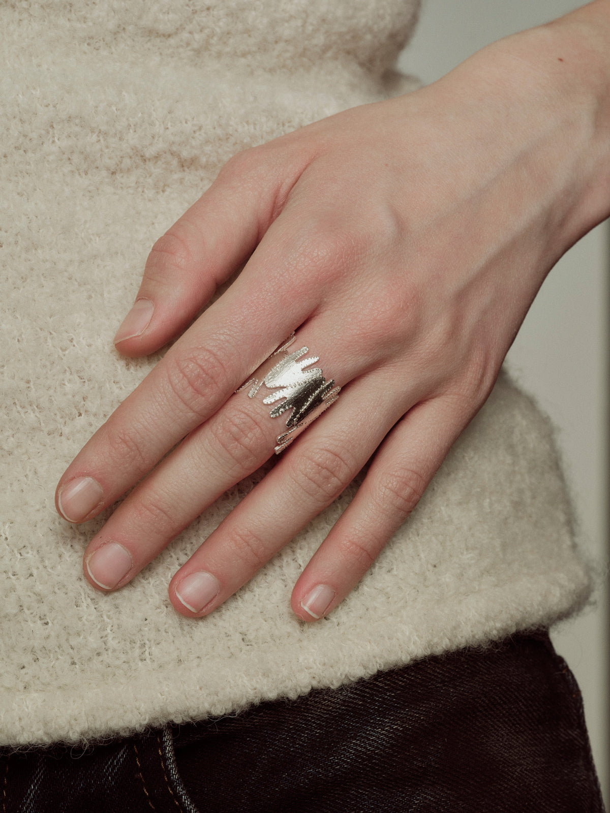 Silver-toned ring with detailed portrait motif on finger