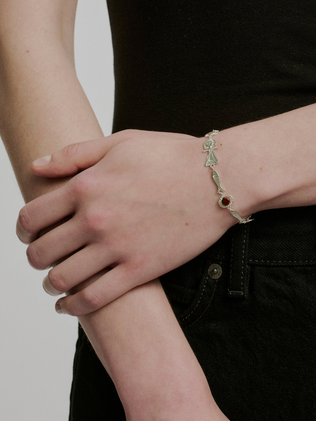 Silver charm bracelet with alternating bow and red stone links, secure clasp