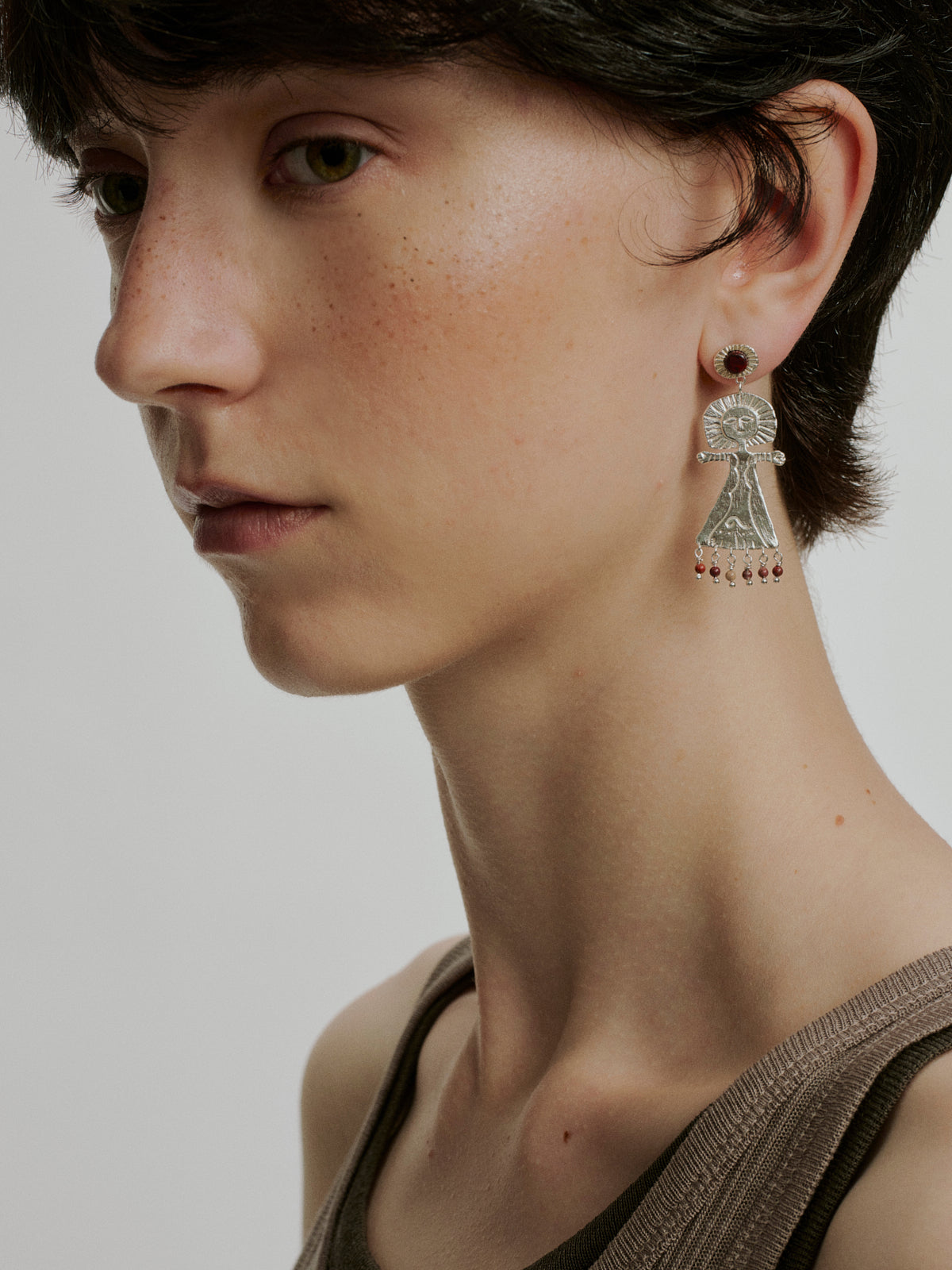Silver deity drop earrings with round red stone and bead fringe, dangling from stud