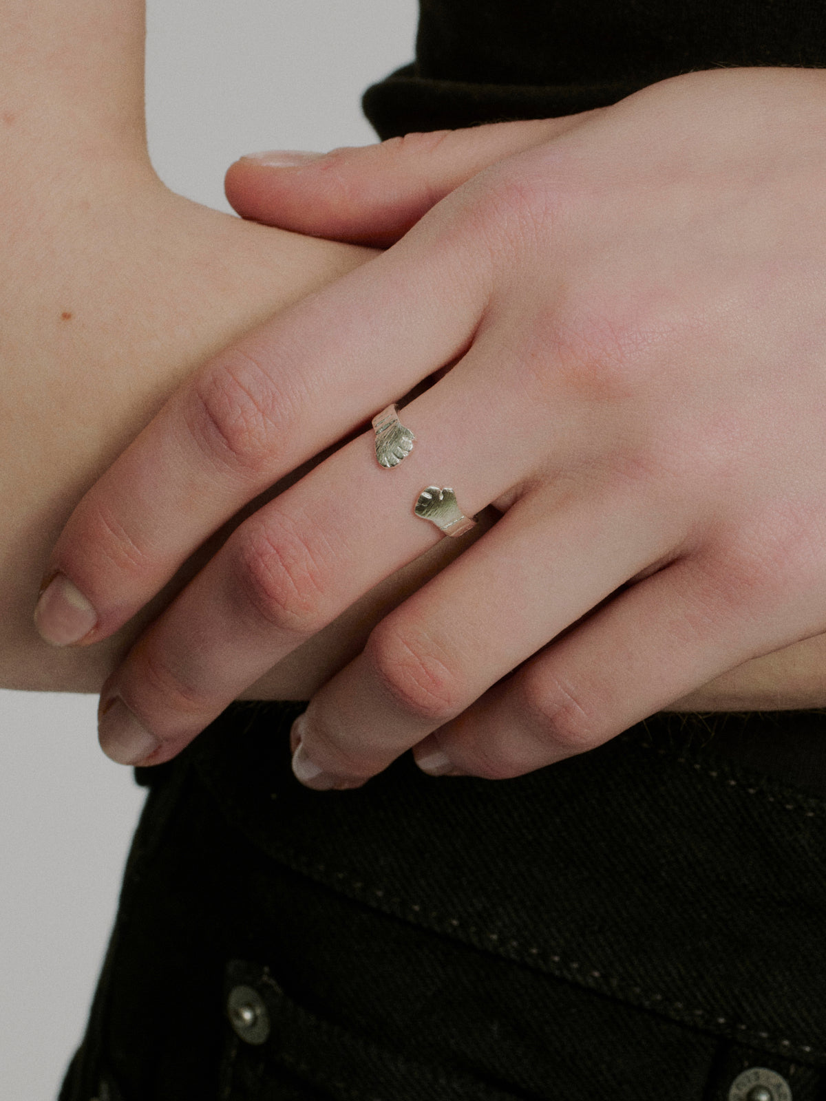 Close-up of silver hug ring pair with small textured centerpiece on stacked bands.