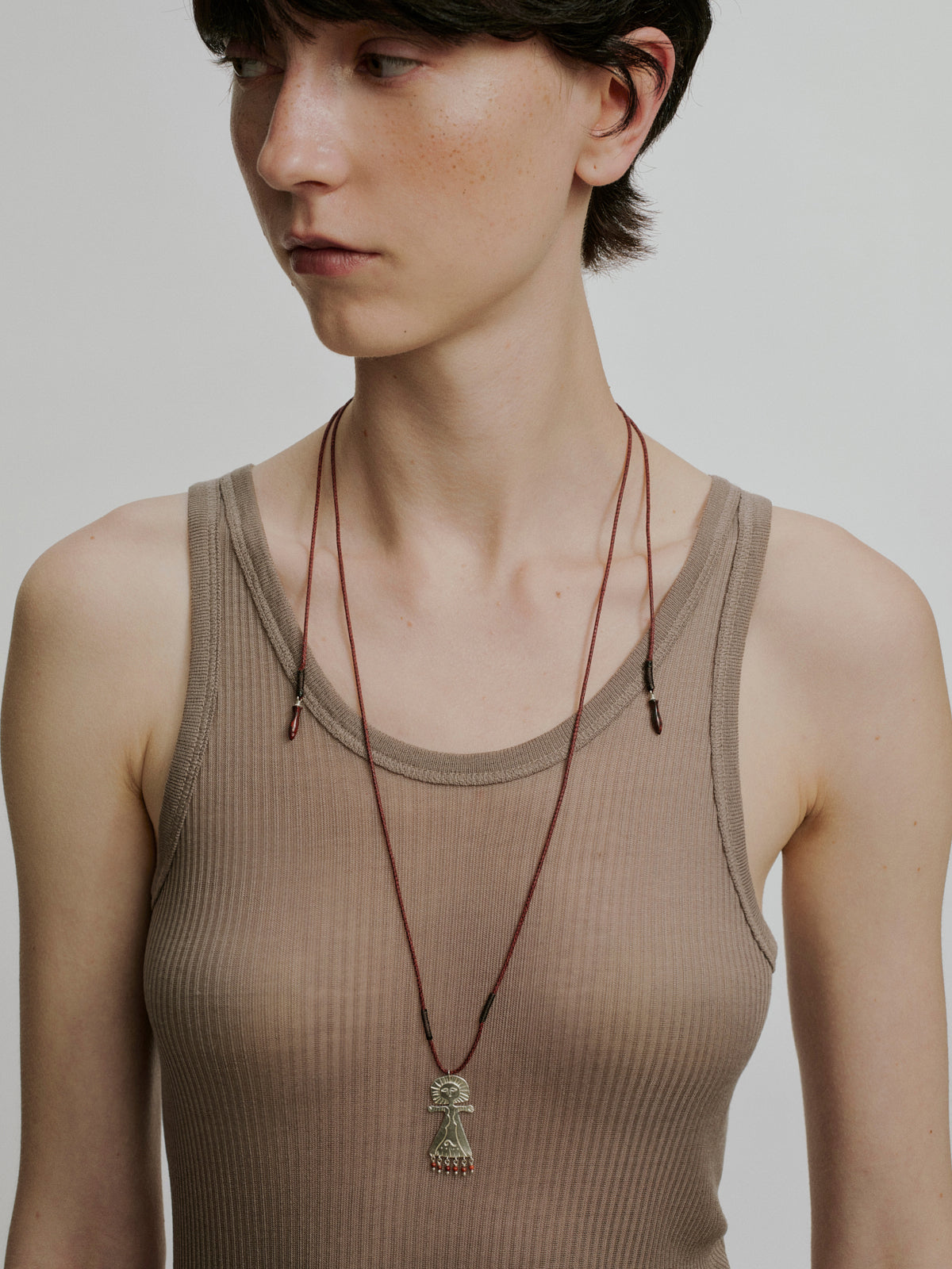 Braided rope necklace with silver-tone deity pendant on red and black cord