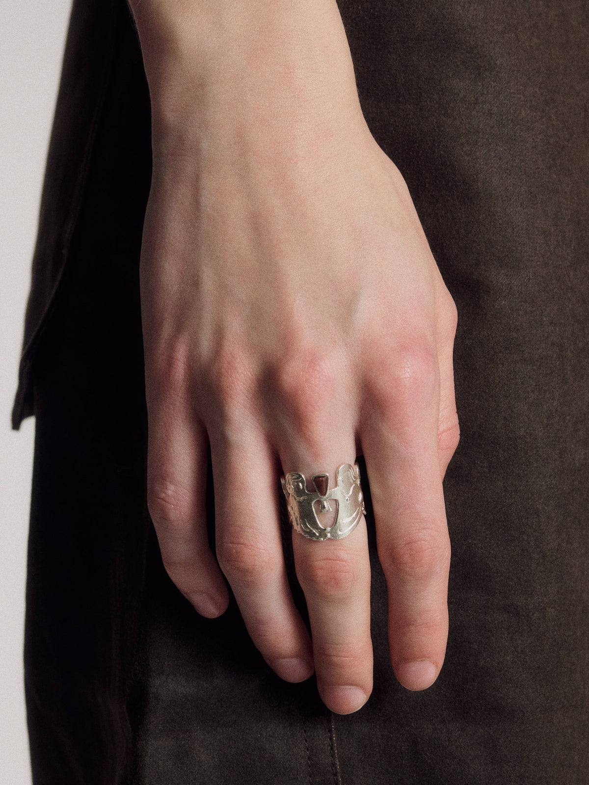 Silver-toned ring with raised animal face and small cutout detailing, on finger