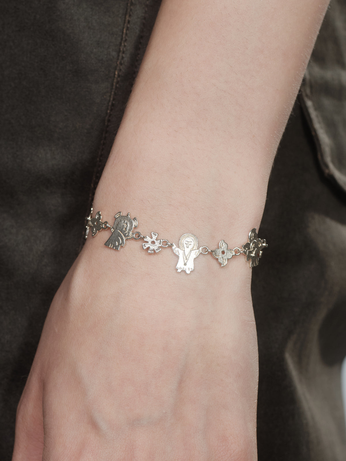 Silver charm bracelet with multiple hanging charms across wrist and forearm