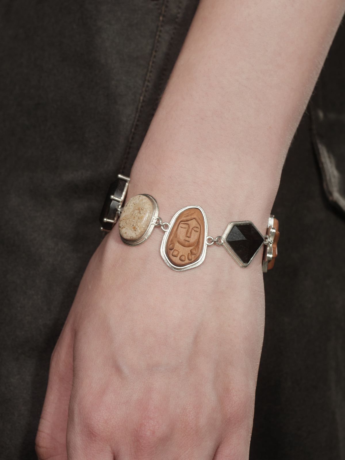 Silver charm bracelet with oval portrait charms and a central black square link