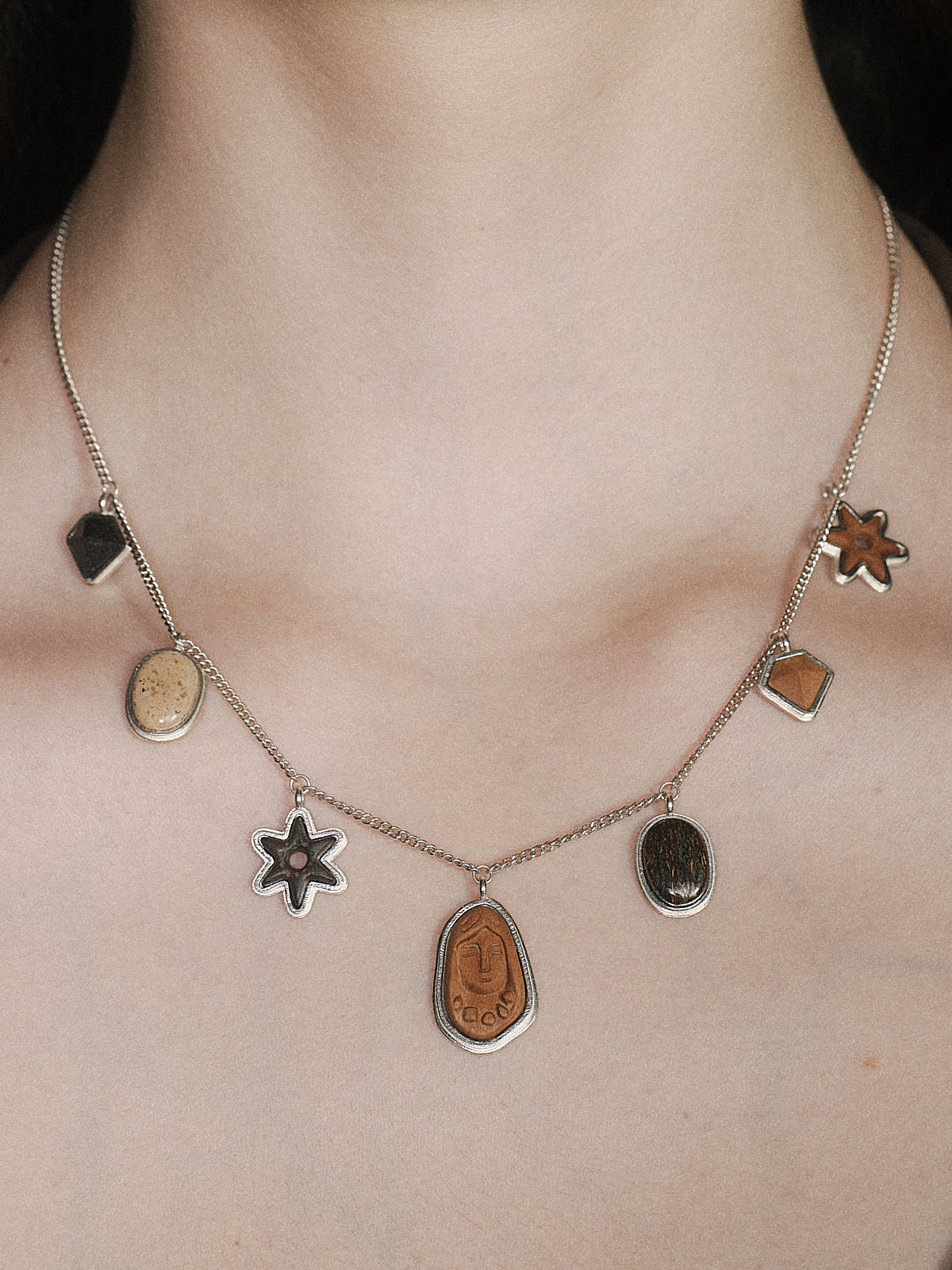 Silver charm necklace with star charms and multiple oval and square pendants